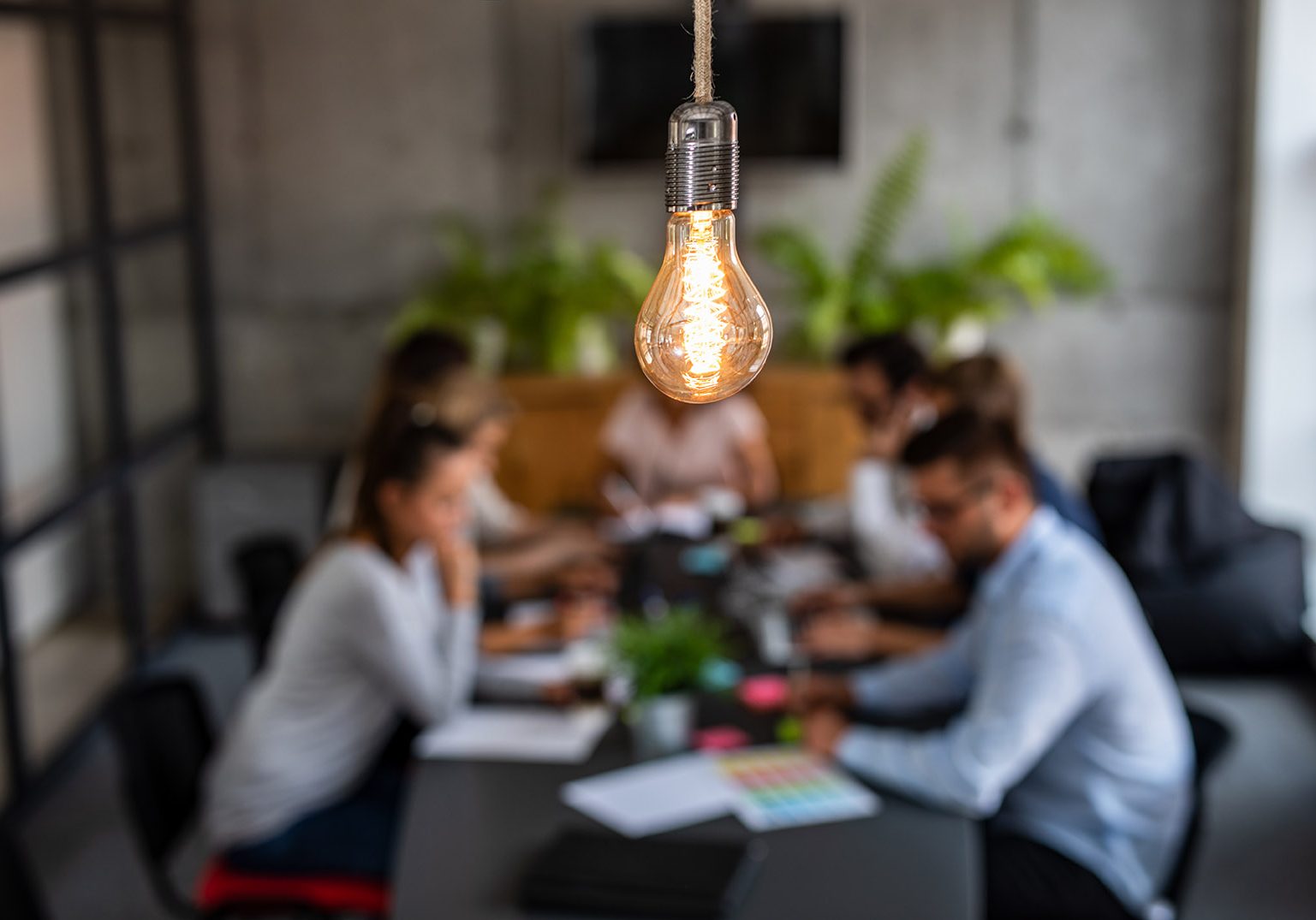 Young business people are discussing together a new startup project. A glowing light bulb as a new idea.